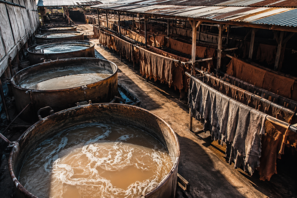 Industrial leather tanning facility showing the sustainable leather production impact through chemical-filled vats and processing equipment used in traditional leather manufacturing.